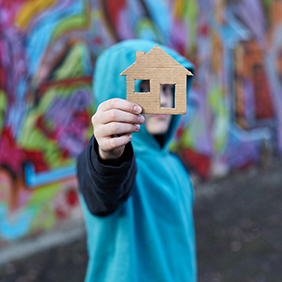 homeless boy holding a house cut out of cardboard