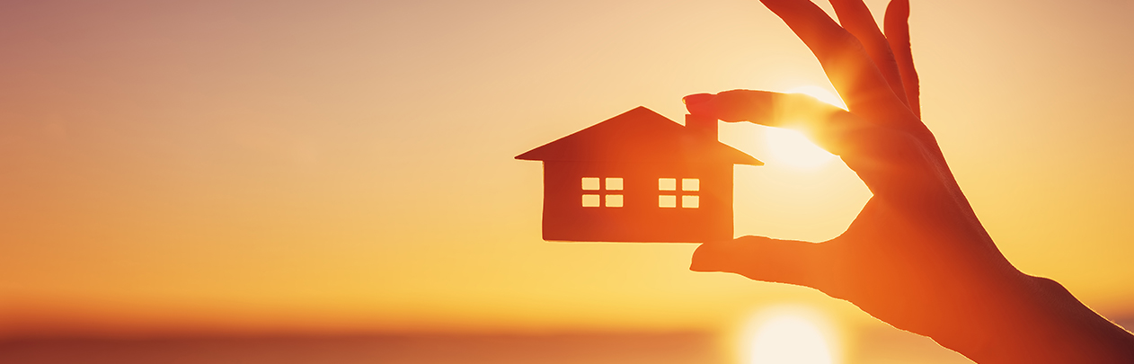 Holding house cutout with sunset in background