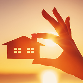 Holding house cutout with sunset in background