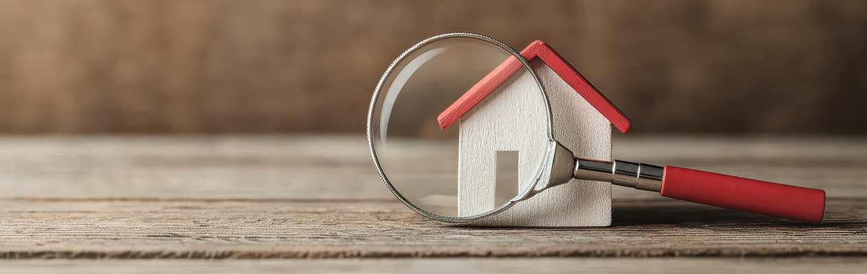 model house with magnifying glass in front