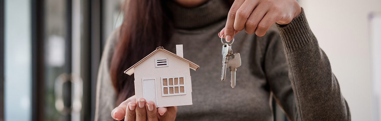 Woman holding model house and keys