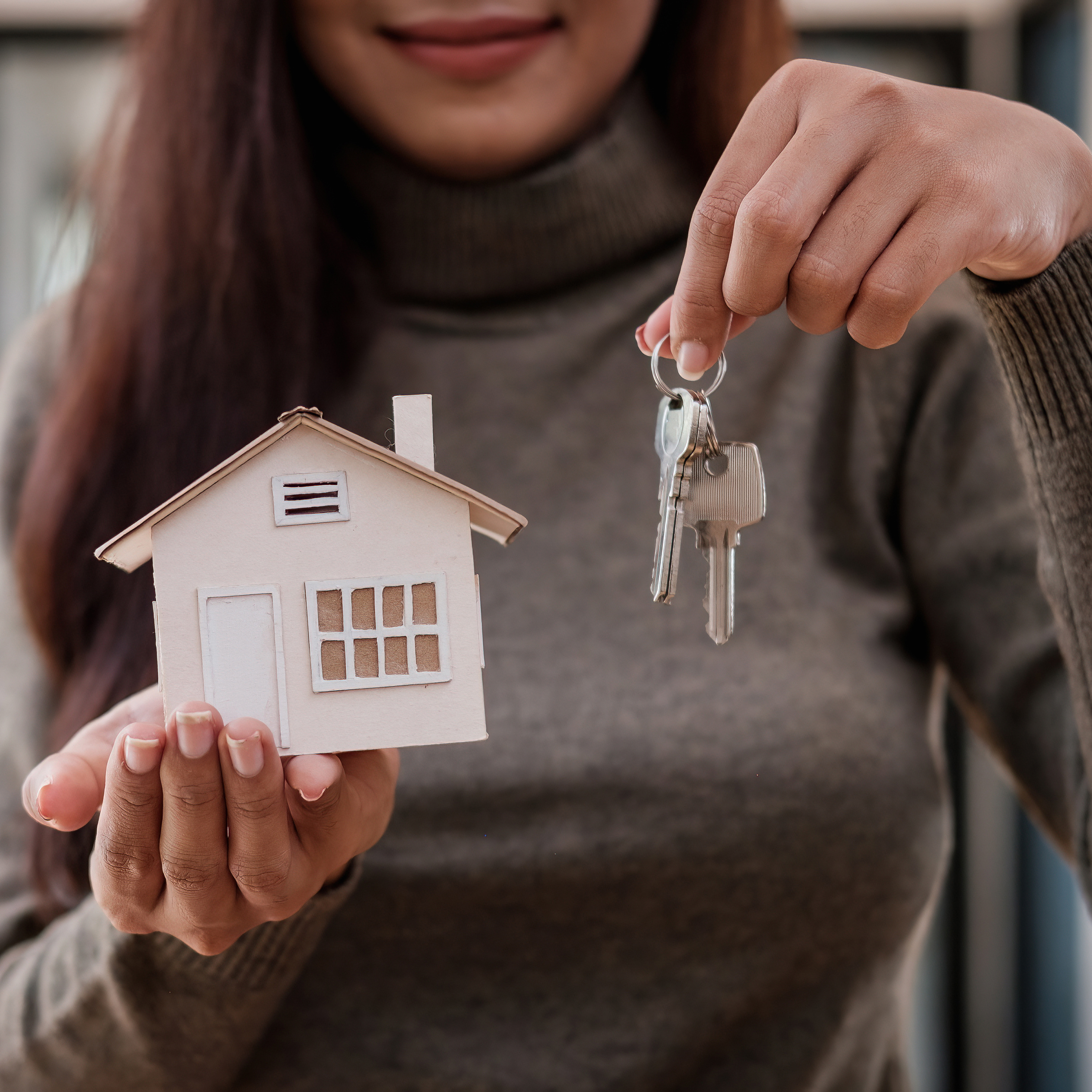 Woman holding model house and keys